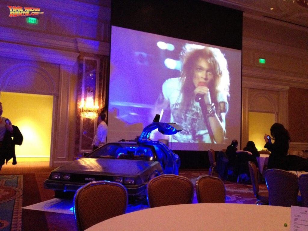 Classic 80's videos blast on the screen as the DeLorean Time Machine rental car stands ready to accept party guests.